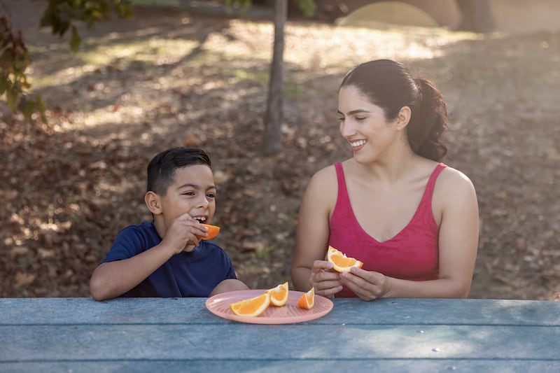 An adult and child share a snack outdoors